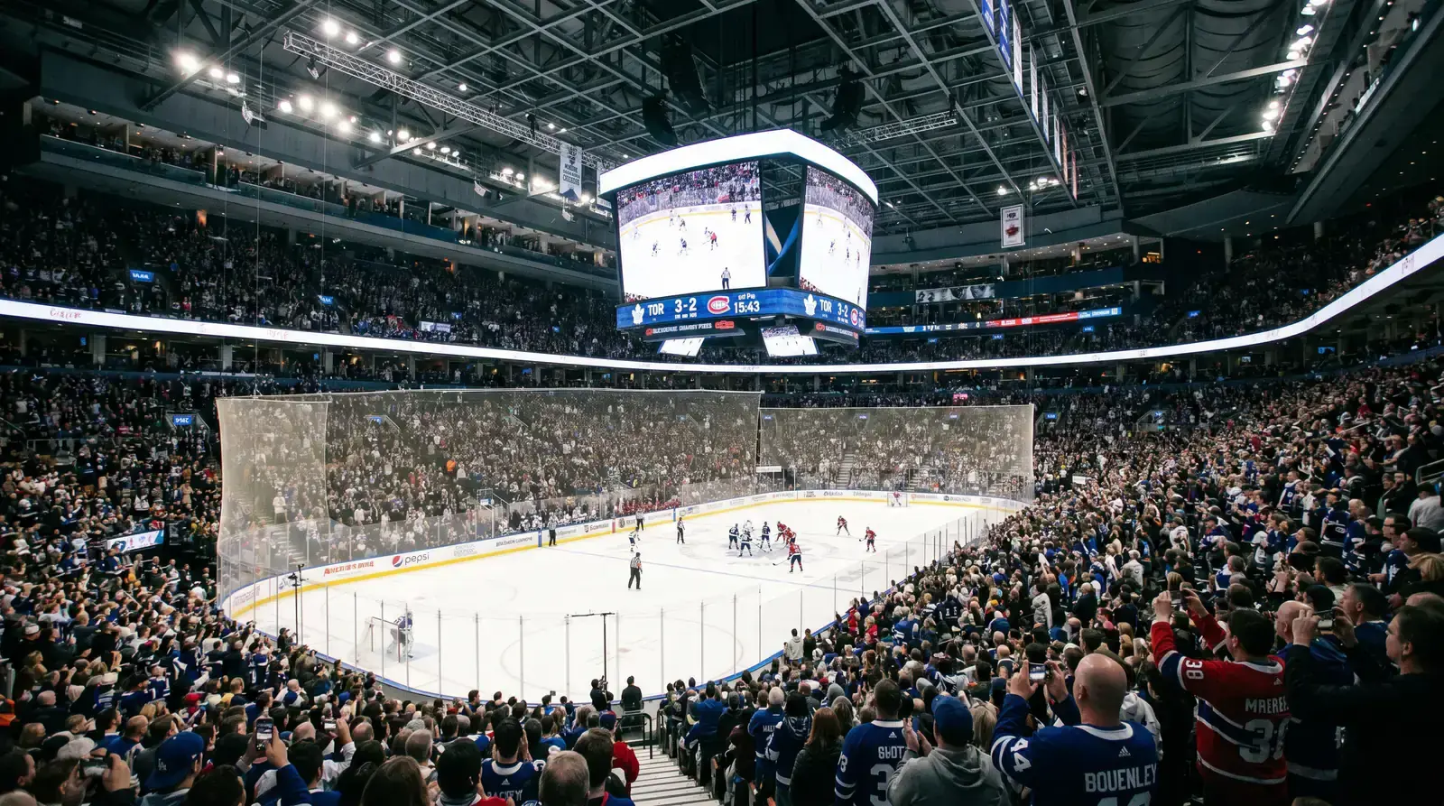 Ice hockey arena during a night game with multiple NHL matches displayed on screens