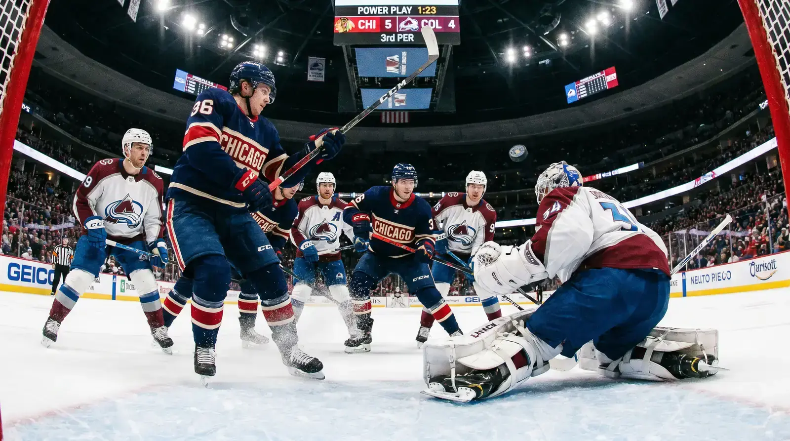NHL power play with five attackers pressing against four defenders near the goal crease